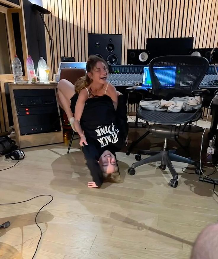 a woman is dancing on the floor in front of some recording equipment and microphones