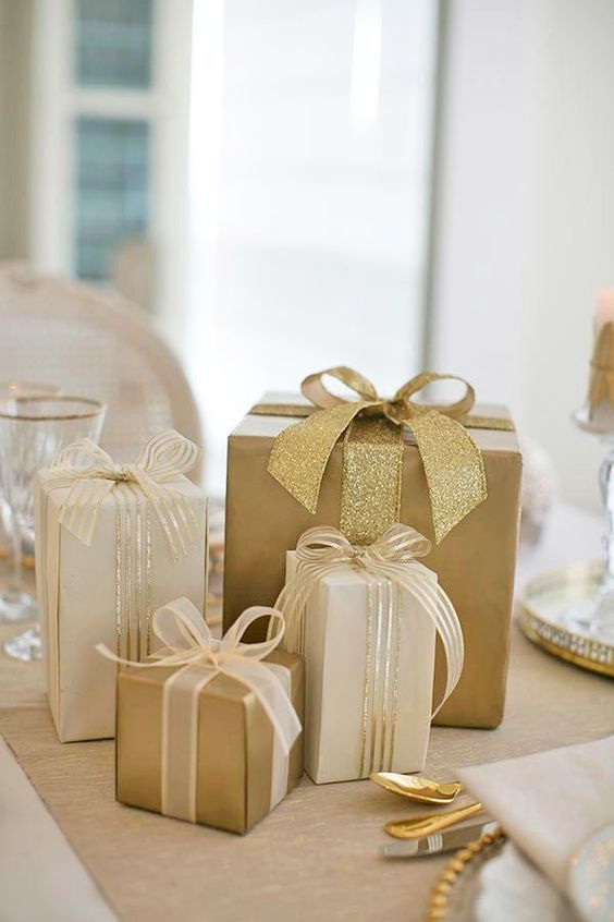 gold and white gift boxes with bows on a table set up for a formal dinner