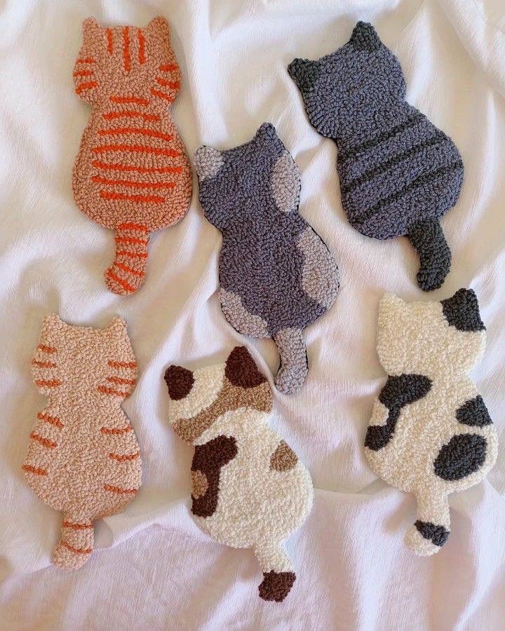 four knitted cats laying on top of a white bed next to eachother