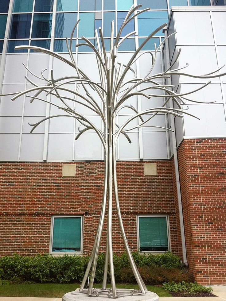 a large metal tree sculpture in front of a building