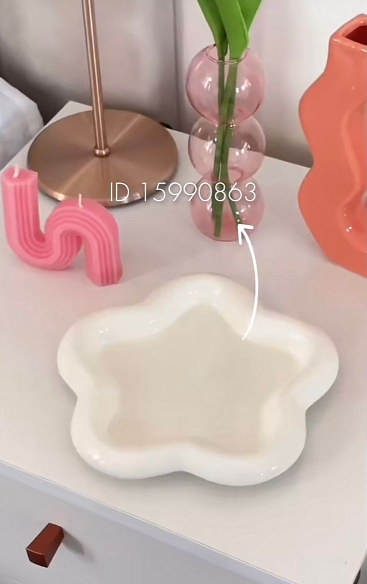 a white table topped with a vase filled with flowers next to a pink candle holder