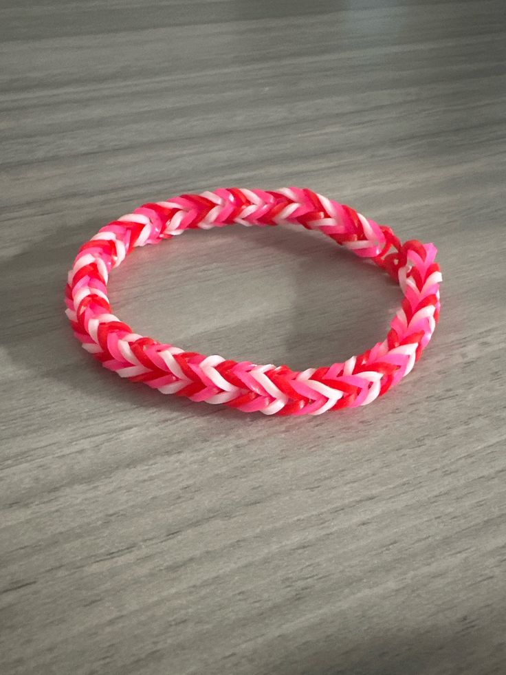 a pink and white bracelet sitting on top of a wooden table