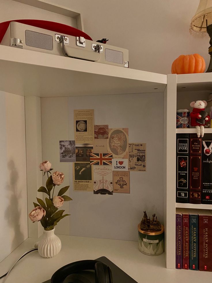 a white desk topped with a laptop computer next to a book shelf filled with books