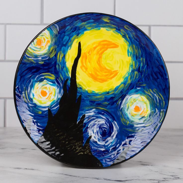 a plate with a painting on it sitting on a counter next to a tile wall