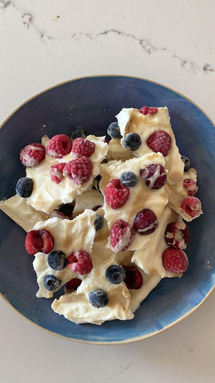 a blue plate topped with fruit covered dessert