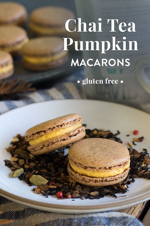 two macarons are on a plate with tea and other items around it,