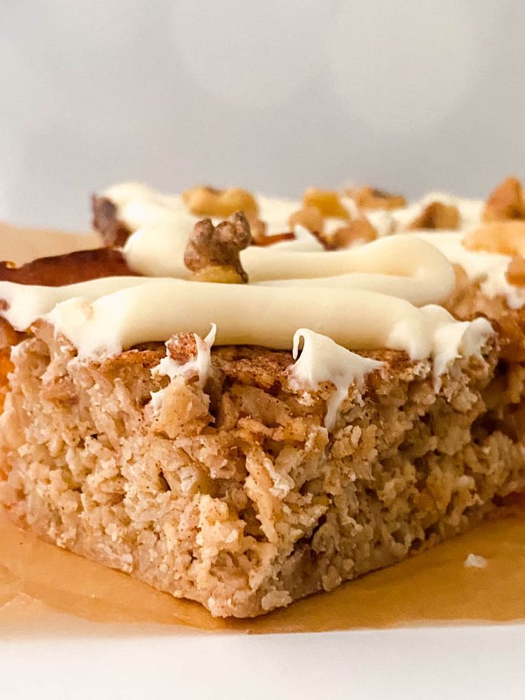 a piece of cake with white frosting and nuts on top is sitting on a plate