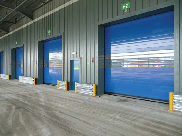 the inside of a storage building with blue doors and yellow poles on either side of the door