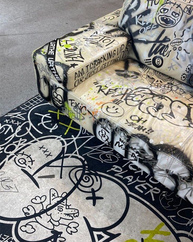 a couch covered in graffiti sitting on top of a rug