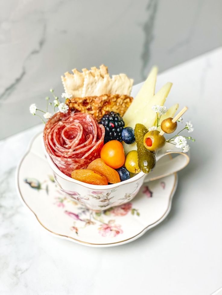 a cup filled with different types of food on top of a saucer next to a plate