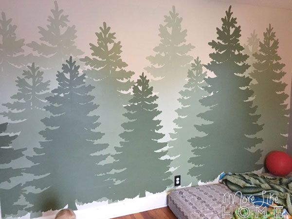 a bedroom with green trees painted on the wall and wood flooring in front of it