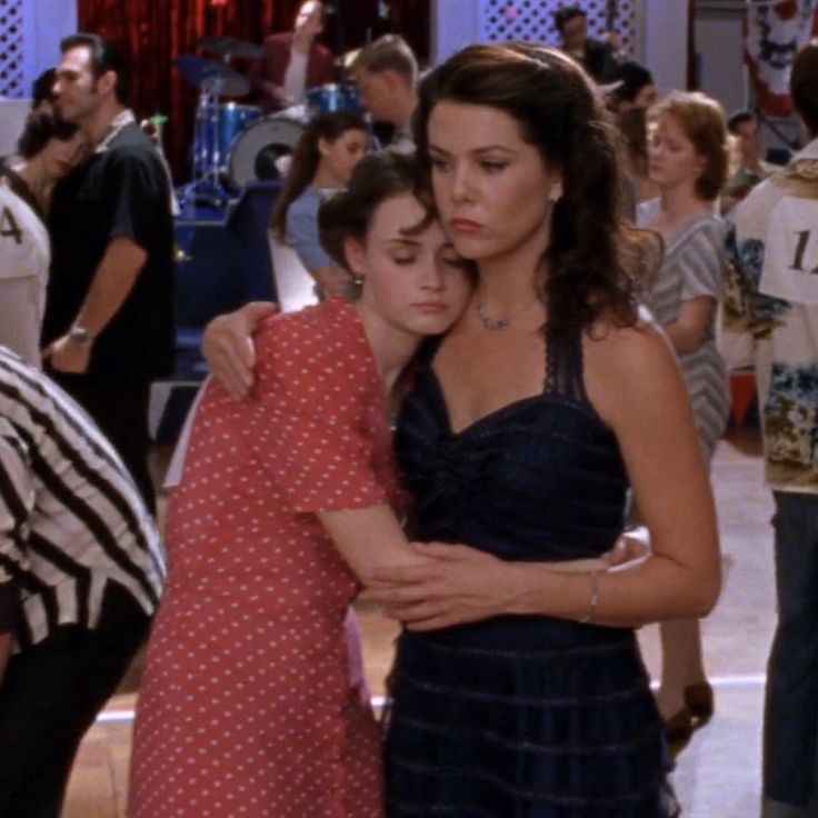 two women hugging each other in a crowded room