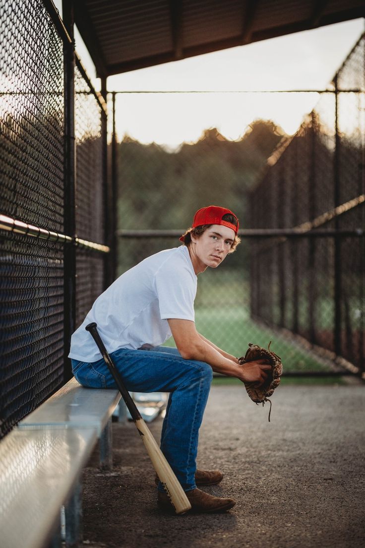 a young man sitting on a bench with a baseball glove and ball in his hand