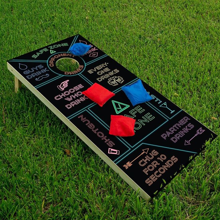 a bean bag toss game sitting on top of a green grass covered field with red and blue pillows