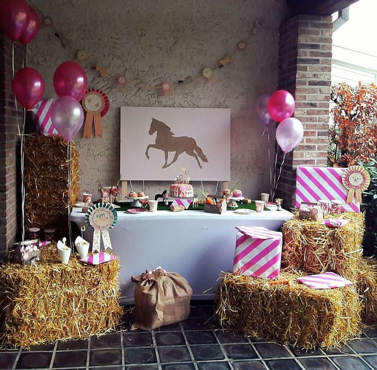 a horse themed birthday party with hay bales, balloons and pink and white decorations