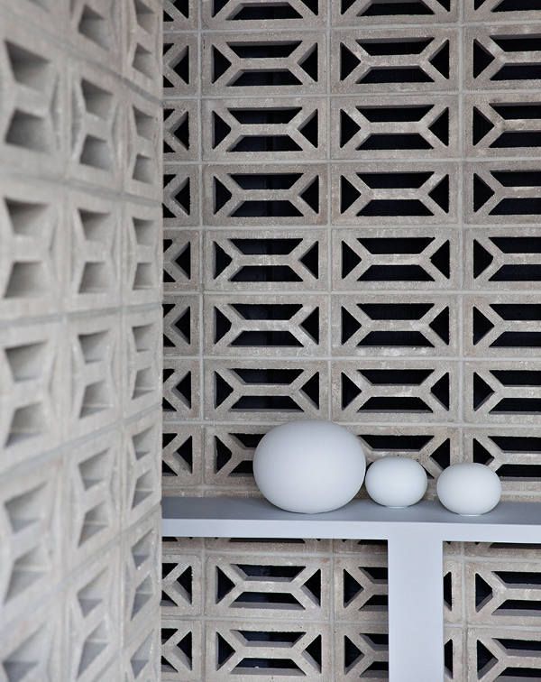 two white eggs sitting on top of a shelf in front of a latticed wall