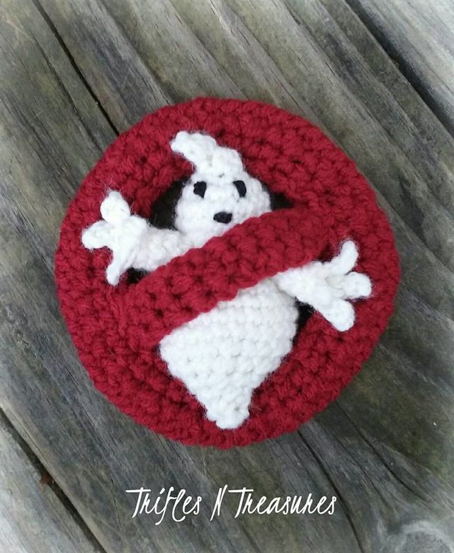 a crocheted red and white sign with a ghost in it on a wooden surface