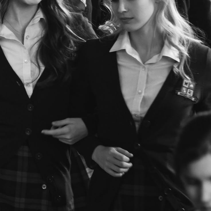 two girls in school uniforms walking down the street with their hands on their hipss