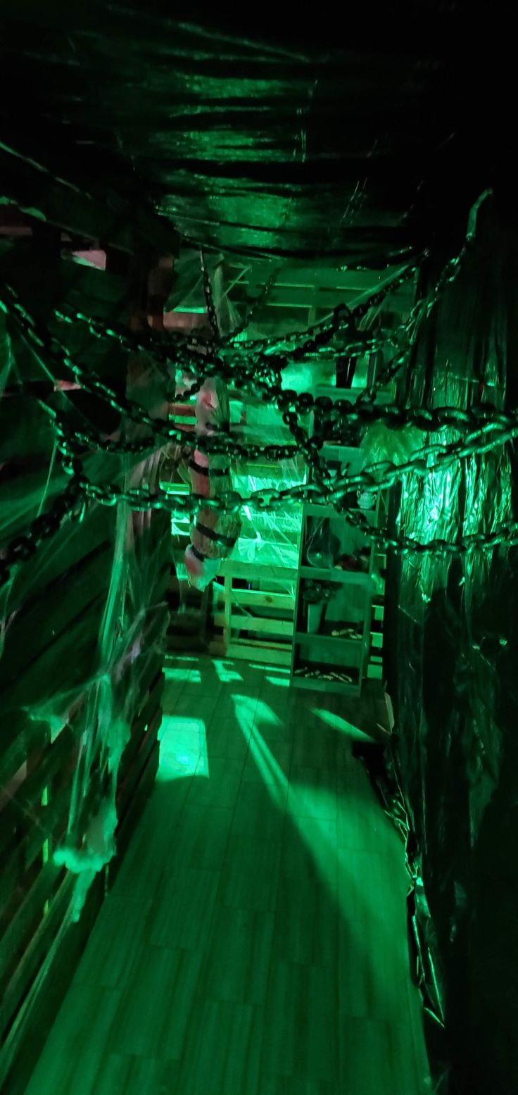 the inside of a building with green lights on it's walls and wood flooring