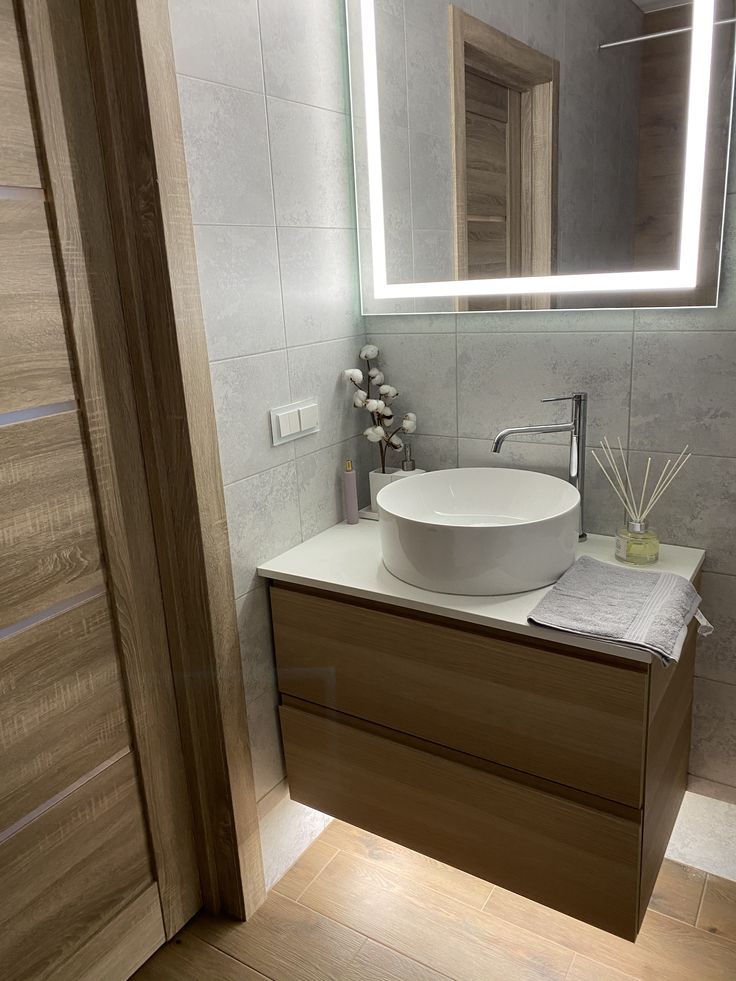 a bathroom sink sitting under a mirror next to a wooden cabinet with drawers and lights on it