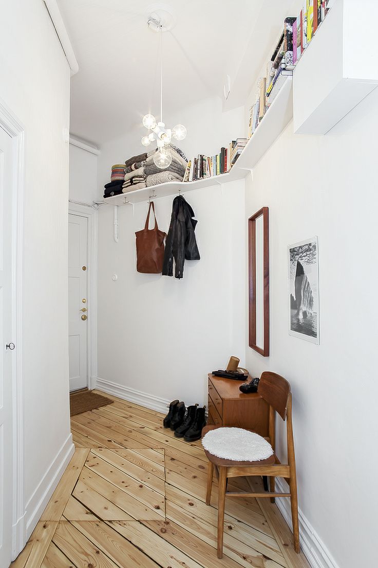 a white room with wooden flooring and a coat rack on the wall next to a chair