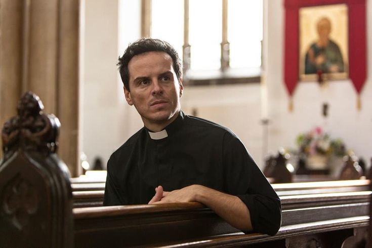 a man sitting in the pews of a church with his hands folded out and looking at the camera