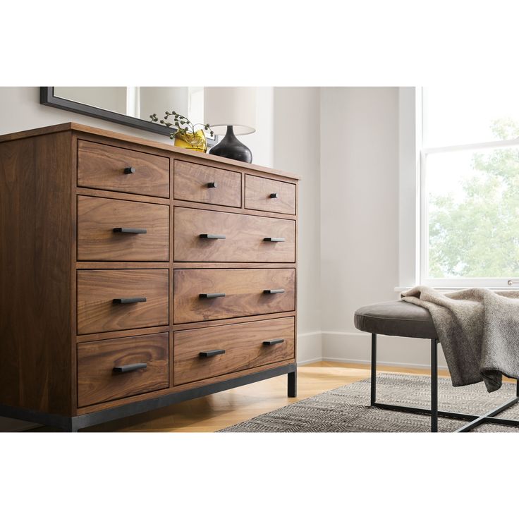 a large wooden dresser sitting on top of a hard wood floor next to a window