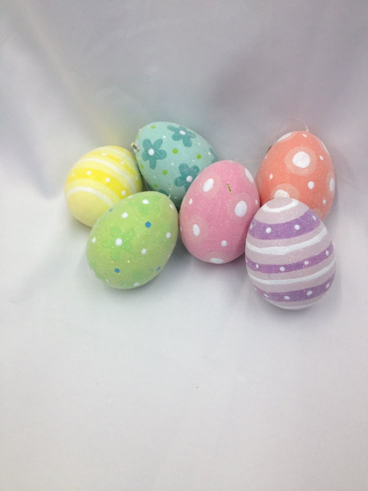 six decorated easter eggs sitting on top of a white surface with polka dots and stripes