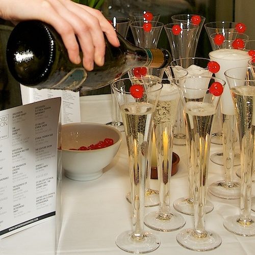 a person pouring champagne into wine glasses on a table with menus and other items