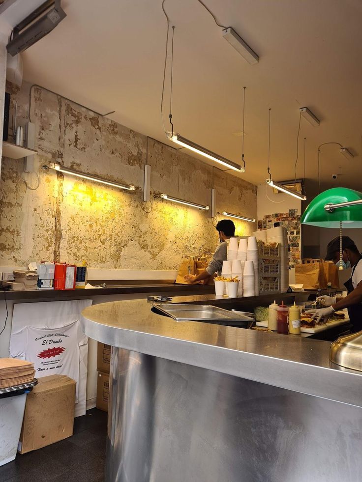 a restaurant kitchen with workers preparing food on the counter and in the background, lights are hanging overhead