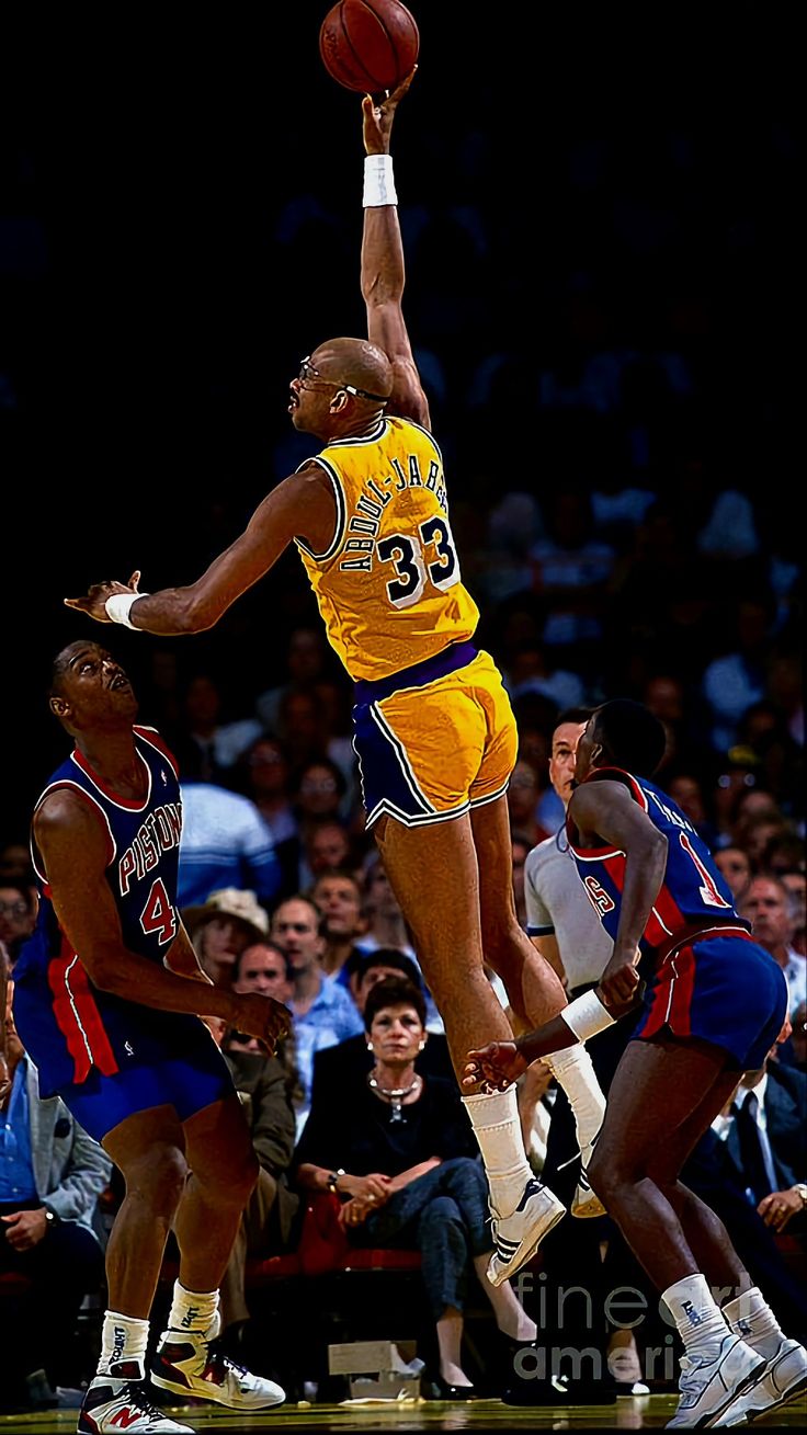 a basketball player jumping up to dunk the ball in front of two other players