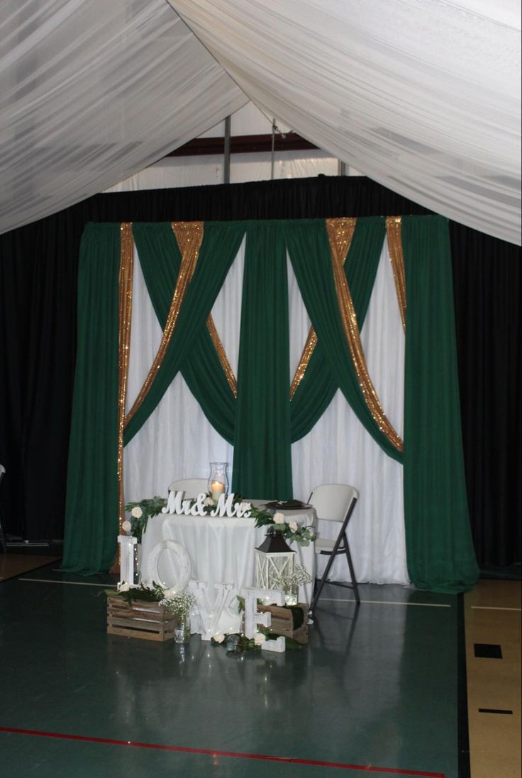 a white table and chairs in front of a green curtain