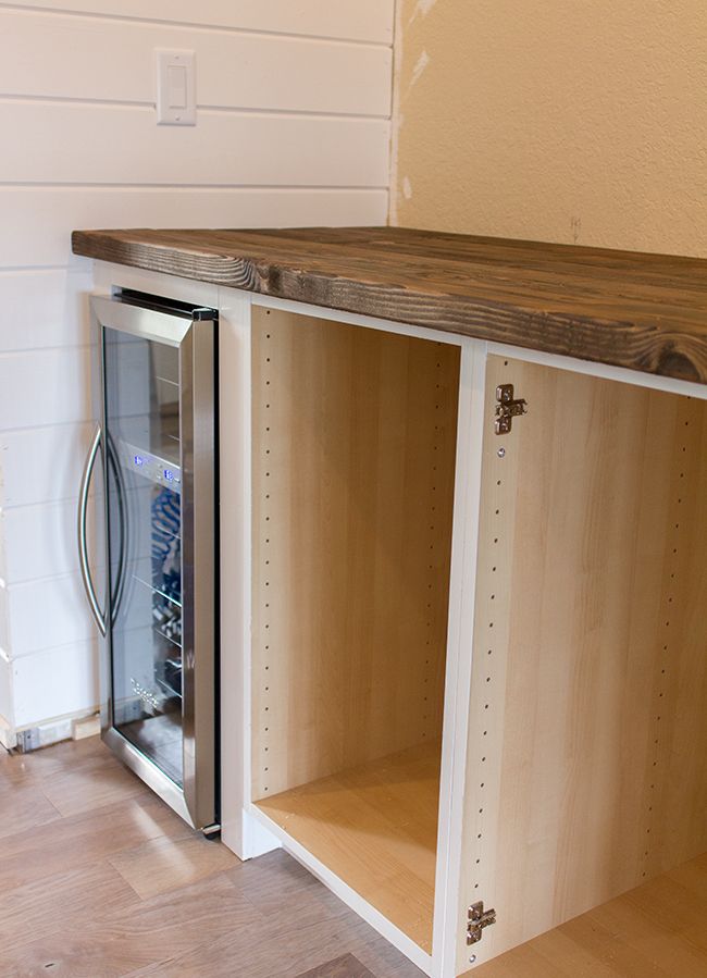 a kitchen cabinet with an icebox in it