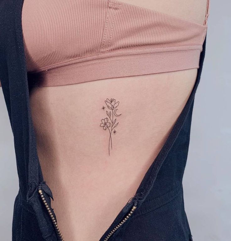 a woman's lower back with a flower tattoo on her left side ribcage