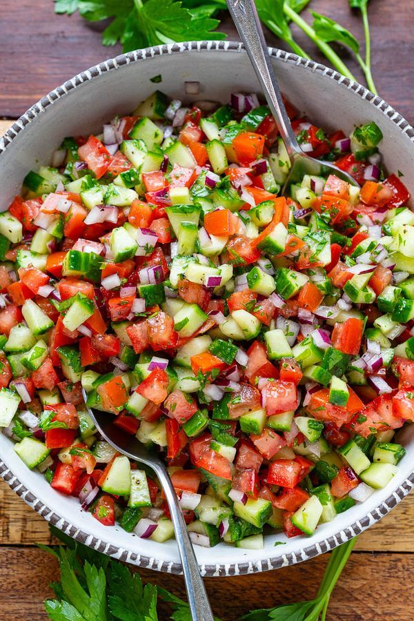 a bowl filled with cucumber, red onion and cilantro on top of a wooden table