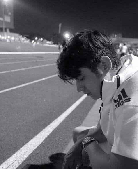 a man kneeling down next to a dog on top of a race track at night