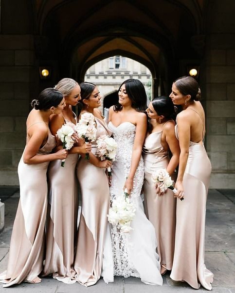 a group of women standing next to each other in long dresses and holding bouquets