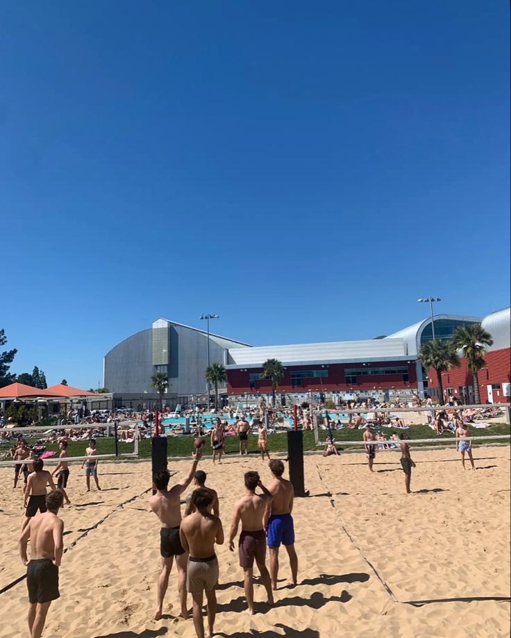 people are playing volleyball on the beach in front of an arena with many spectators watching