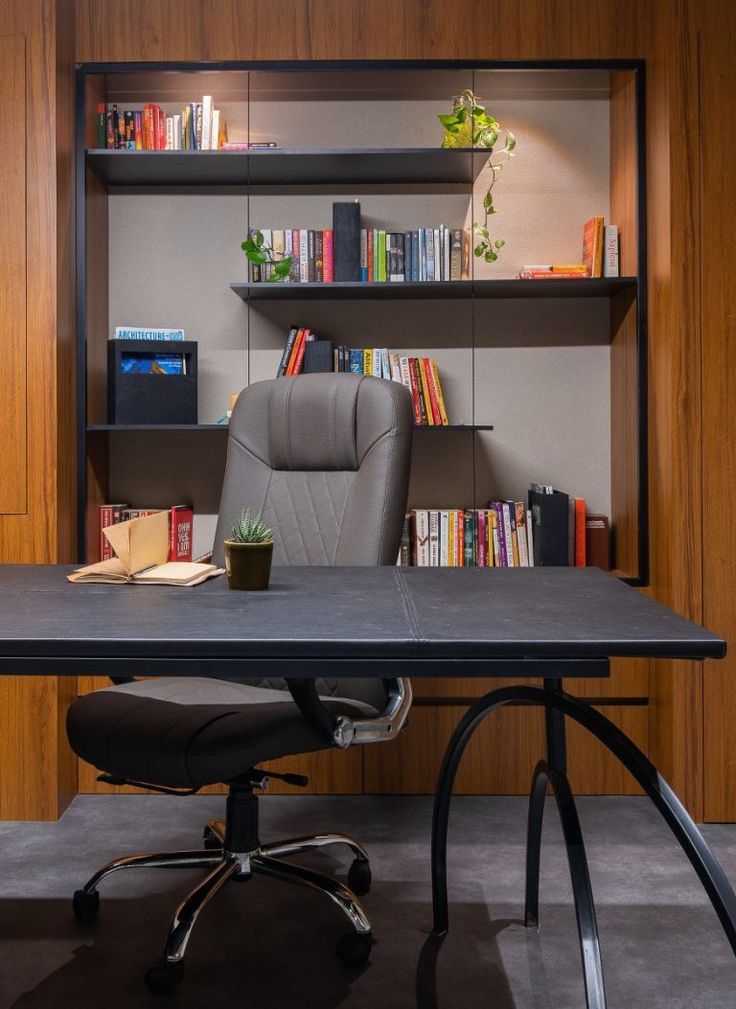 an office desk with a chair and bookshelf