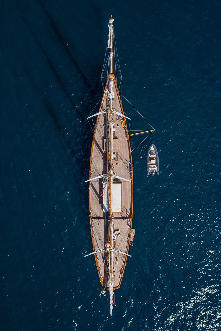 an aerial view of a sailboat in the middle of the ocean with two people on it