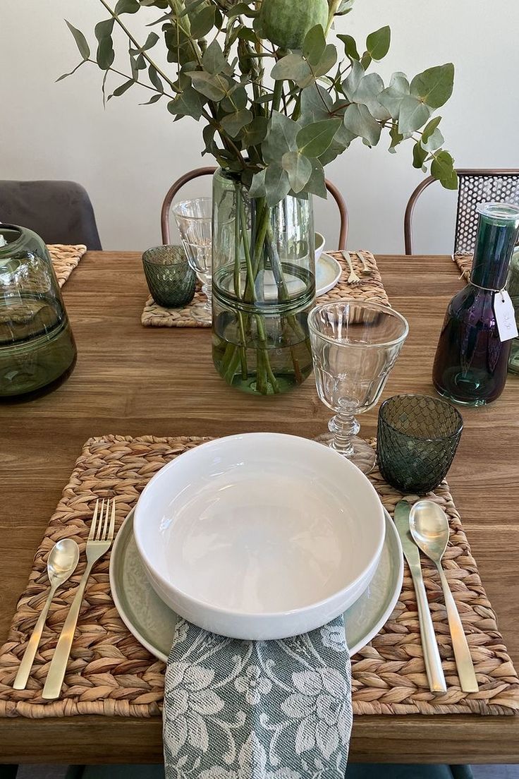 a table set with place settings and flowers in vases