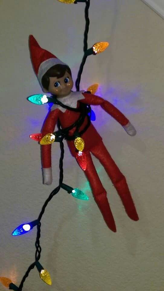 an elf is hanging on the ceiling with christmas lights