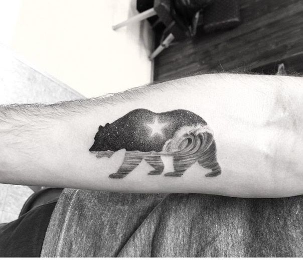 a black and white photo of a bear tattoo on the left arm with stars in it