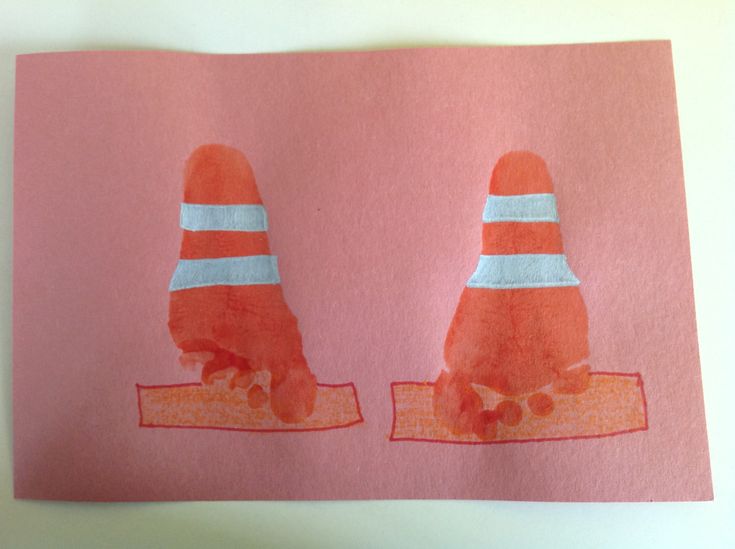 two children's handprints on pink paper with orange and white cones over them