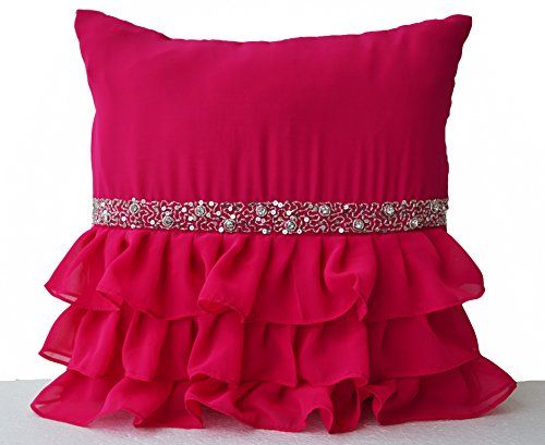 a pink pillow with ruffles and sequins on the bottom, sitting on a white surface