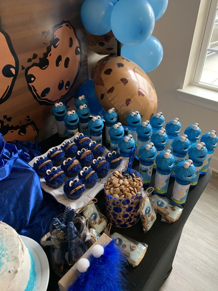 a table topped with lots of blue and white desserts next to balloon shaped balloons