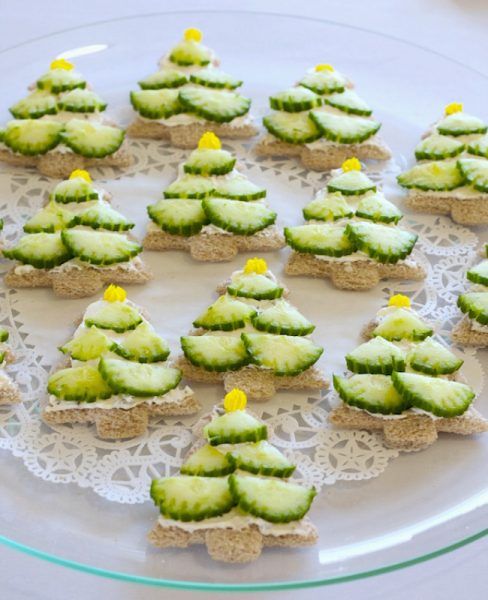 small cookies decorated with cucumber are on a glass platter