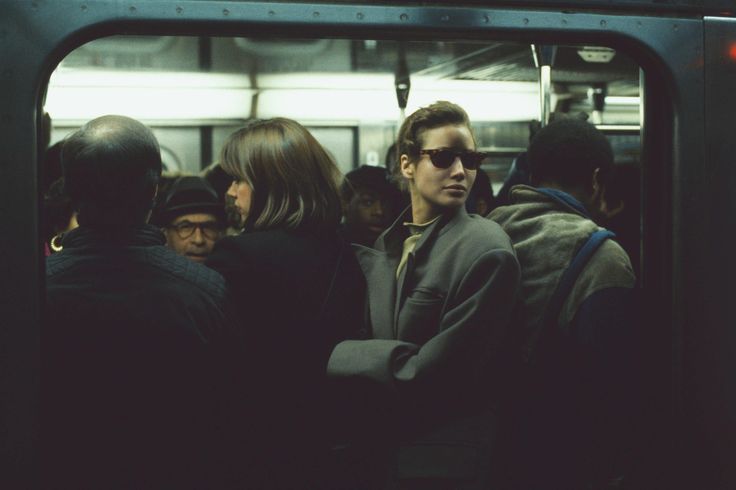 a group of people standing on a subway train next to each other and looking out the window