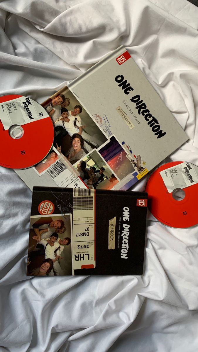 there are two dvds and an orange disk on the bed with white sheets in front of it