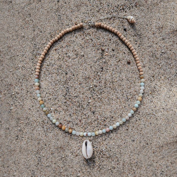 Originally founded as an arts colony, Laguna Beach is a mix of chill beach town and funky bohemian culture, offering some of the clearest blue water and the most relaxing days Southern California has to offer. MATERIALS blue and natural colored Amazonite with cowrie shell and natural wood on a 15" wire, finished with a 1.5" sterling silver extender chain with a ring clasp and tulip shell. Every stone is unique, which means that each bracelet is too. You can expect your jewelry to be one of a kin Bohemian Shell-shaped Beaded Necklace For Vacation, Handmade Multi-strand Shell Necklace For Beach, Ocean-inspired Shell Necklace With Colorful Beads, Handmade Turquoise Shell Necklace Ocean-inspired, Handmade Turquoise Shell Necklace, Ocean-inspired, Bohemian Culture, Clear Blue Water, Cowrie Shell, Relaxing Day